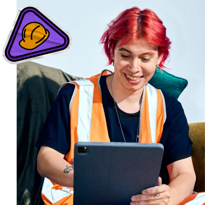 A person with red hair wearing an orange high-visibility vest smiles while looking at a tablet. A small purple badge icon with a yellow hard hat is displayed in the top left corner, symbolizing construction or safety training.
