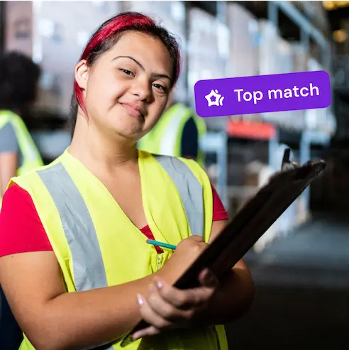 Smiling warehouse worker with a clipboard wearing a safety vest, labeled "Top match."